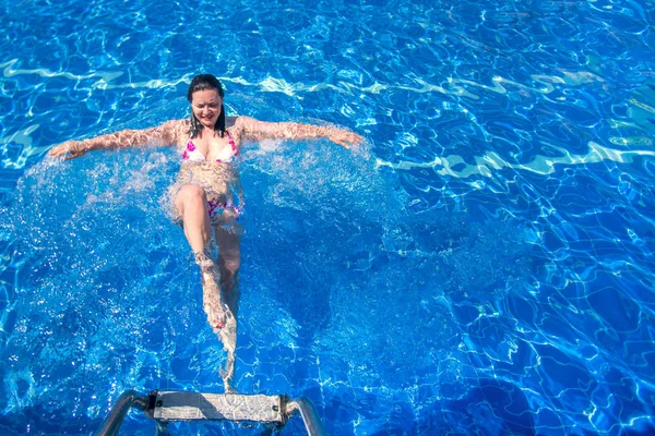 穿着比基尼漂浮在游泳池里的褐发女郎 — 图库照片