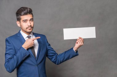 Bir boş bir parmağı ile beyaz gösteren mavi elbiseli Genç çekici adam gri bir arka taraftan oturum açmak