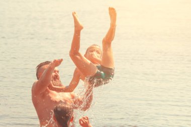 Suya atlamak. Erkek ve çocuk eğleniyor ve suya su sıçratıyorlar. Yaz tatili kavramı