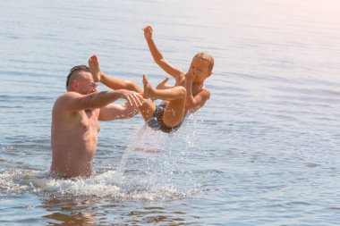 Suya atlamak. Erkek ve çocuk eğleniyor ve suya su sıçratıyorlar. Yaz tatili kavramı