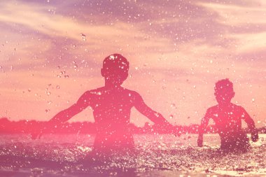 Çocukların silueti eğlenip denize sıçratıyor. Yaz tatili ve sağlıklı yaşam tarzı konsepti.