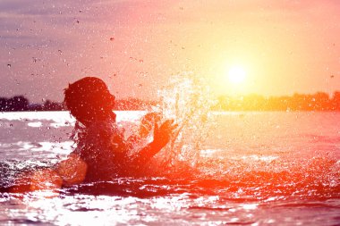 Suya atlamak. Çocuk eğleniyor ve suya su sıçrıyor. Yaz tatili kavramı