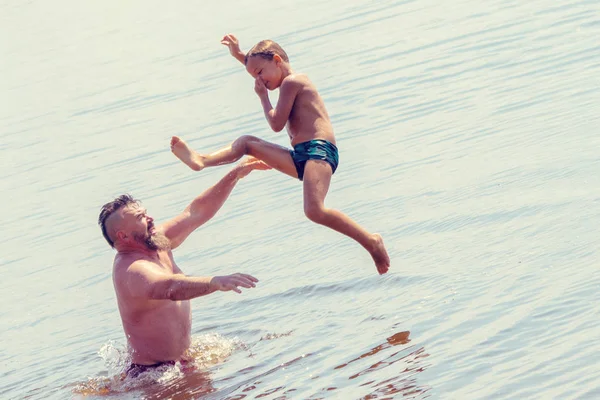 Jumping in the water. Man and boy are having fun and splashing in the water. Summer holiday concept