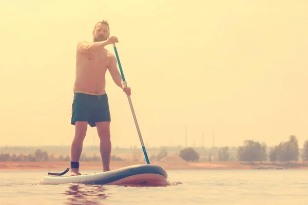 Sup surfing. Stand up paddle boarding. Surfer on sup board on the river.