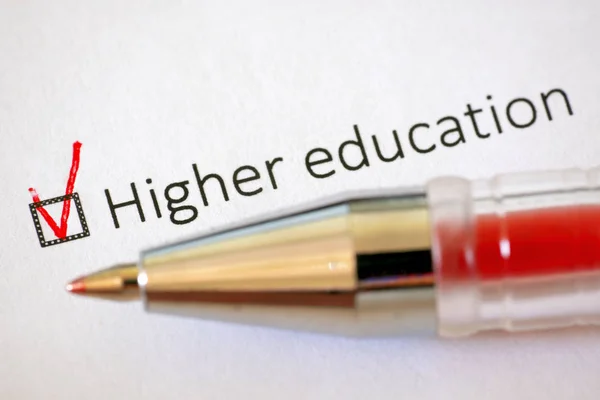 Questionnaire. Red pen and the inscription HIGHER EDUCATION with check mark on the white paper