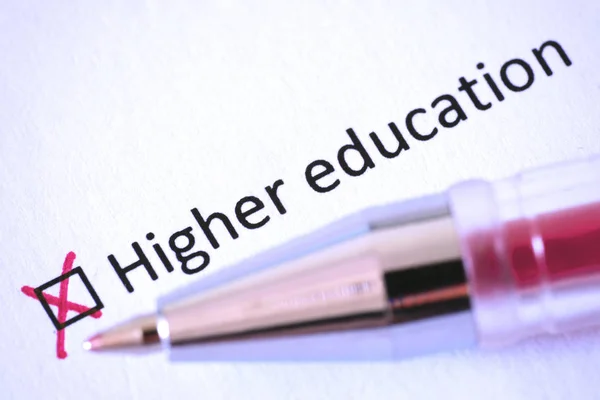 Questionnaire. Red pen and the inscription HIGHER EDUCATION with cross on the white paper