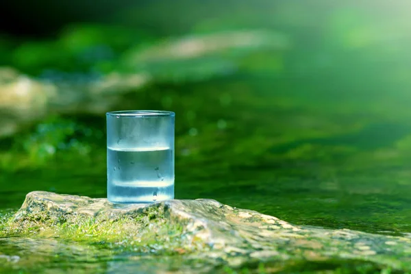 The glass of cool fresh water on nature background