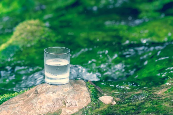 The glass of cool fresh water on nature background