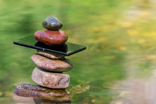 水の中の石とスマートフォンのバランス — ストック写真