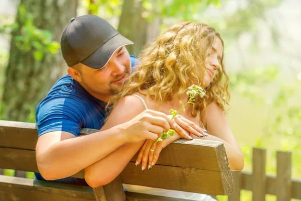 The couple quarreled while sitting on a park bench. A man gives flowers to a woman as a sign of reconciliation. Relationship problems