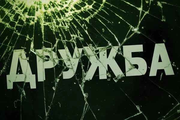 Il testo russo "L'amicizia" sul vetro rotto . — Foto Stock