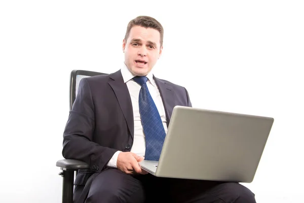Empresario sentado en una silla con un portátil en la mano, hablando . —  Fotos de Stock