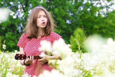 Çiçekler ve ağaçlar arasında ukulele ile Singing kız.