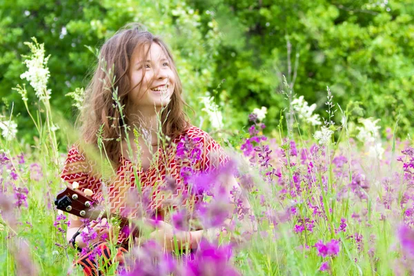 Смішна дівчина з укулеле на лузі серед квітів . — стокове фото