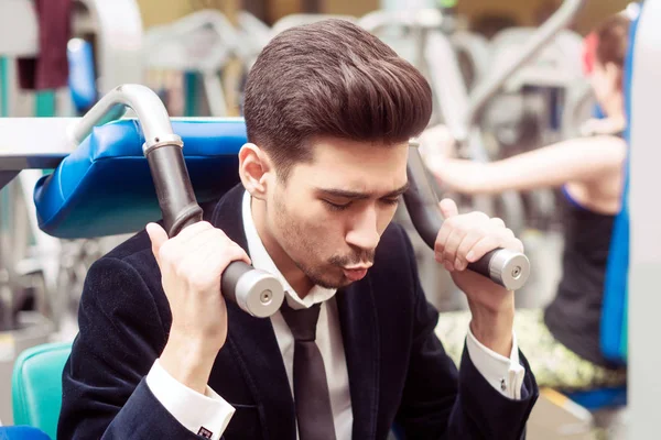 Takım elbiseli ve spor salonundaki beyaz gömlekli adam. Bir exer gerçekleştirir — Stok fotoğraf