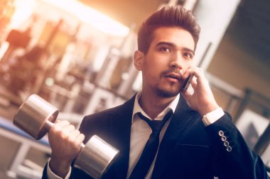 Elinde bir dambıl ile klasik bir takım elbiseli Adam th konuşuyor