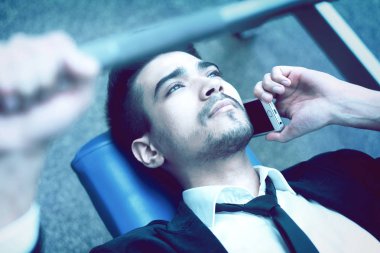 Beyaz gömlekli ve takım elbiseli, bir barbell ve 