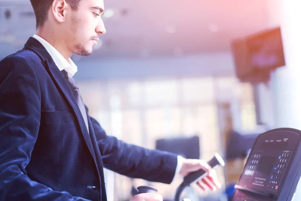 Young man in a white shirt and suit on the treadmill at the gym. — Stock Photo, Image