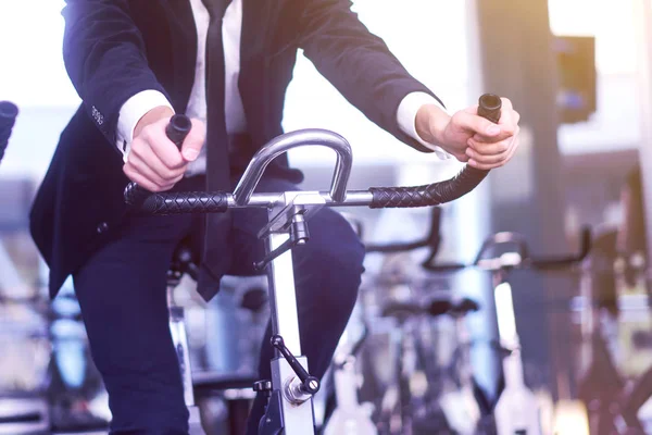 Ung man i en vit skjorta och kostym på en stationär cykel i — Stockfoto