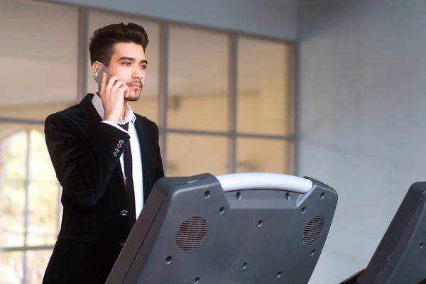 Businessman in white shirt and suit with phone on the treadmill — Stock Photo, Image