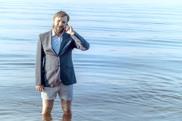 Bearded man in a jacket and underwear knee-deep in water with a — Stock Photo, Image