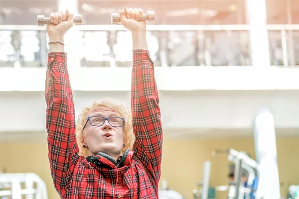 Homem louro encaracolado fraco em uma camisa quadriculada vermelha com esforço liftin — Fotografia de Stock