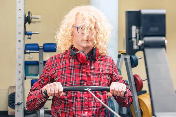 Curly loira cara em uma camisa vermelha no treinamento no ginásio . — Fotografia de Stock