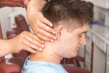 Berber dükkanındaki genç adam. Saç kesimi sonrası rahatlatıcı masaj.