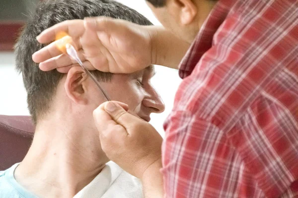 Jonge man bij de kapper. Ontharing in de oren. — Stockfoto