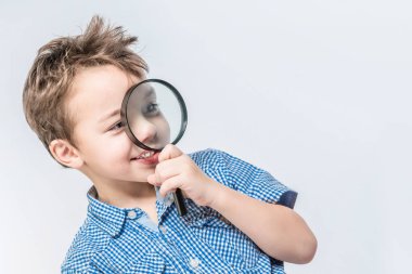 Gülümseyen çocuk beyaz bir backgroun üzerinde büyüteç içine bakıyor