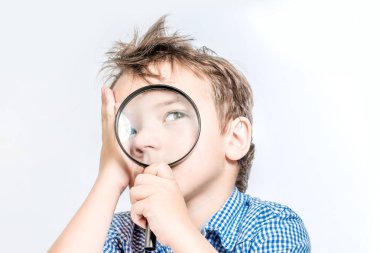 Sevimli çocuk düşünceli bir beyaz üzerinde bir büyüteç içine bakıyor