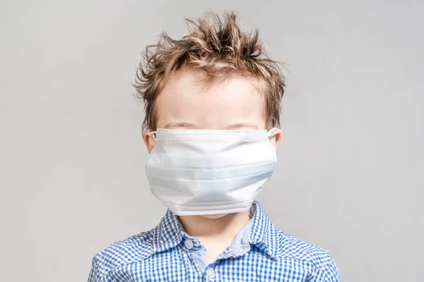 Хлопчик із закритою медичною маскою обличчя на сірому фоні в — стокове фото