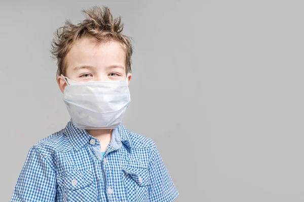 Хлопчик дитина в медичній масці на сірому фоні в студії . — стокове фото