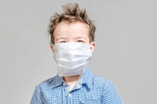 Хлопчик з медичною маскою на обличчі на сірому тлі в — стокове фото