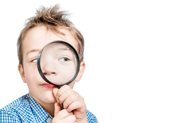 Ragazzo divertente guardando in una lente di ingrandimento su uno sfondo bianco . — Foto Stock