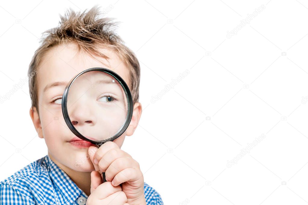 Funny boy looking into a magnifying glass on a white background.
