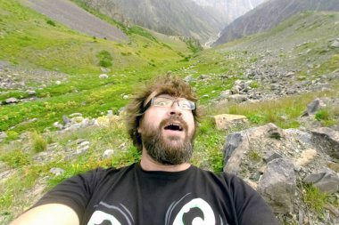 Korkmuş sakallı adam dağlarda selfie yapıyor.