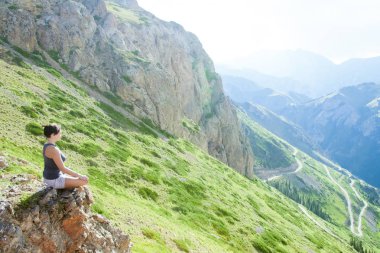 Kadın dağlarda üstte oturan meditasyon.
