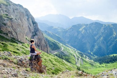 Kadın bir dağ çıkıntısı üzerinde oturan meditasyon.