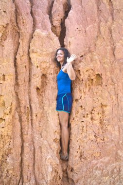 Gülümseyen kız dağın yarığında duruyor.