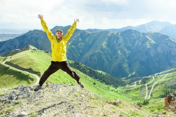 Gülümseyen adam dağların bir arka plan üzerinde atlar.
