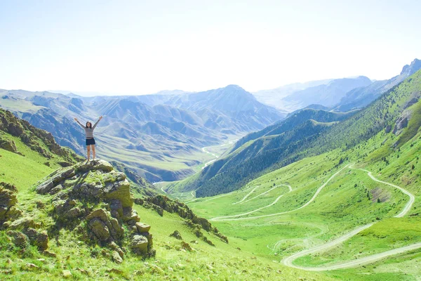 Una chica con las manos en alto está en la cima de una de las montañas . —  Fotos de Stock