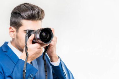 Beyaz arka planda kamera ile mavi takım elbiseli çekici adam.