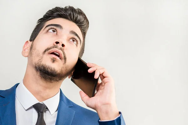 A young man in a blue suit talking on the phone in the studio on — Stock Photo, Image