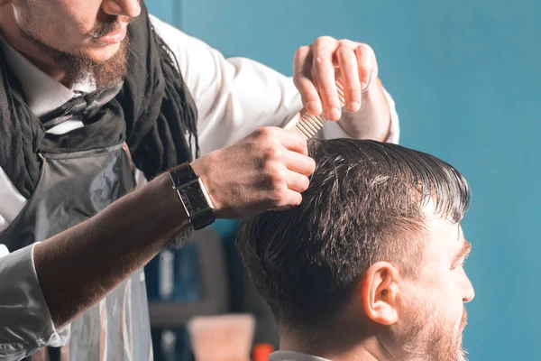 Kapper kammen het haar van een man. Voorbereiding op een kapsel. — Stockfoto