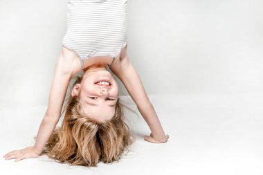 Gri bir arka plan üzerinde eller üzerinde duran gülümseyen kız.