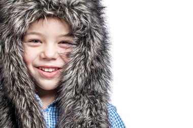 Smiling little boy in a fur hat on a white background.