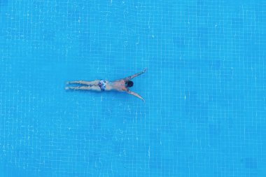 Bir adam yüzme havuzunda su altında yüzer..