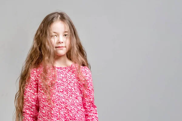 Menina bonito com cabelos longos em um vestido vermelho em um fundo cinza. É — Fotografia de Stock