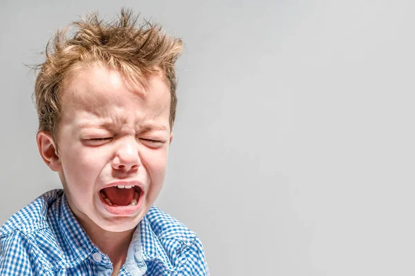 Chico llorón sobre un fondo gris  . — Foto de Stock